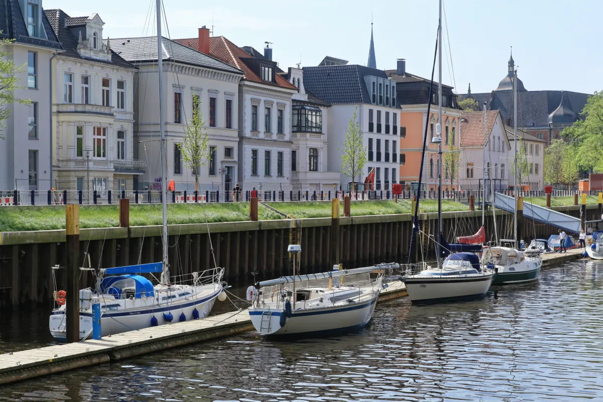 Historische Häuser an der Huntestraße in Oldenburg mit Segelbooten im Hafen.